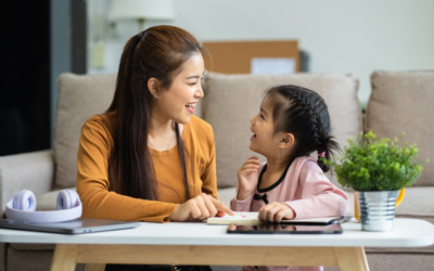 Adorable attentive Little girl writing in notebook and using laptop while doing homework.