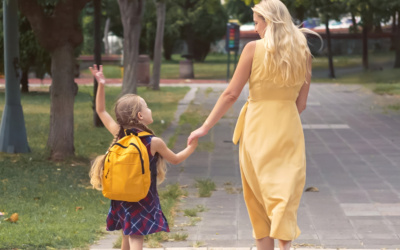 Mother and daughter, backpacks on, joyfully walk through the park to school.